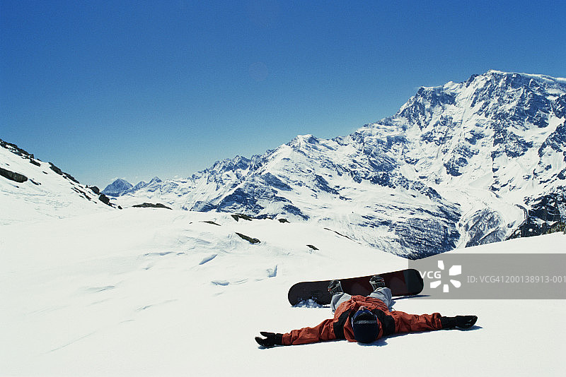 躺在雪地上的男子单板滑雪者图片素材