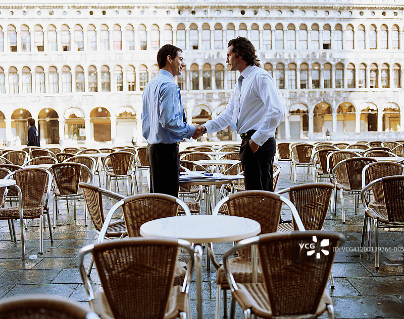 两位商人在户外咖啡馆握手（侧面）图片素材