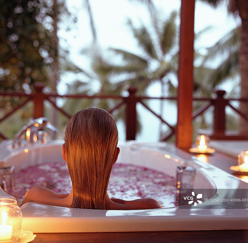 年轻女人在热水浴缸中放松，后视图图片素材