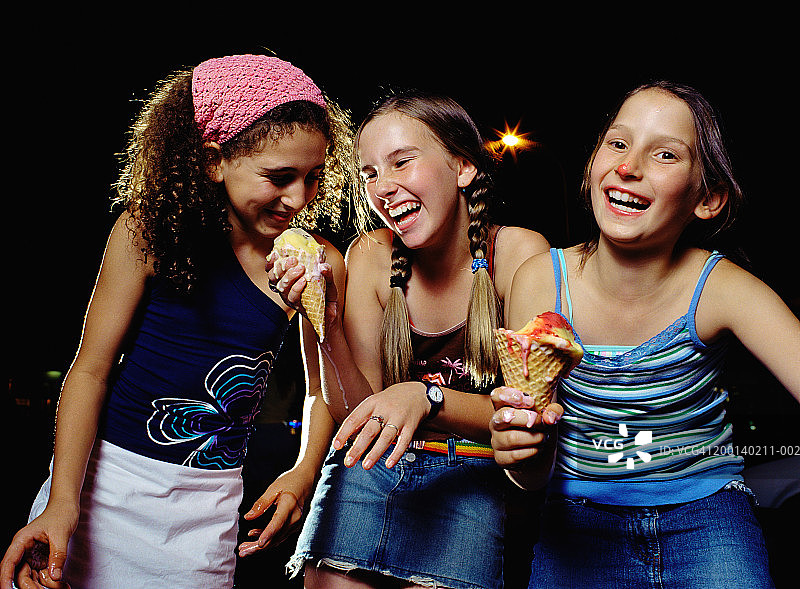 三个（5-10岁）正在欢笑的女孩，两个拿着融化的冰淇淋图片素材