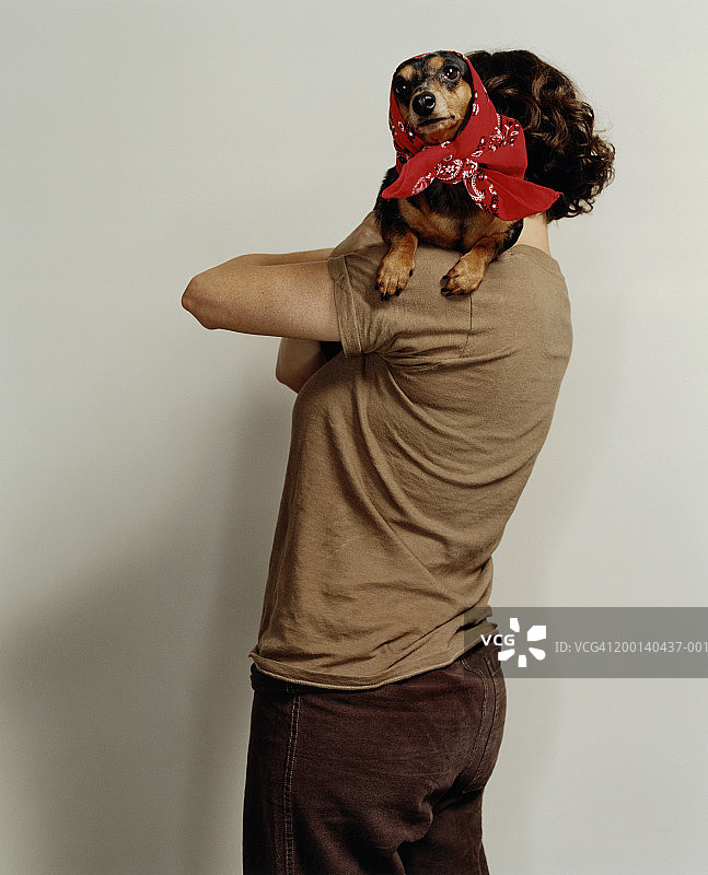 女人肩上扛着戴着头巾的腊肠犬图片素材