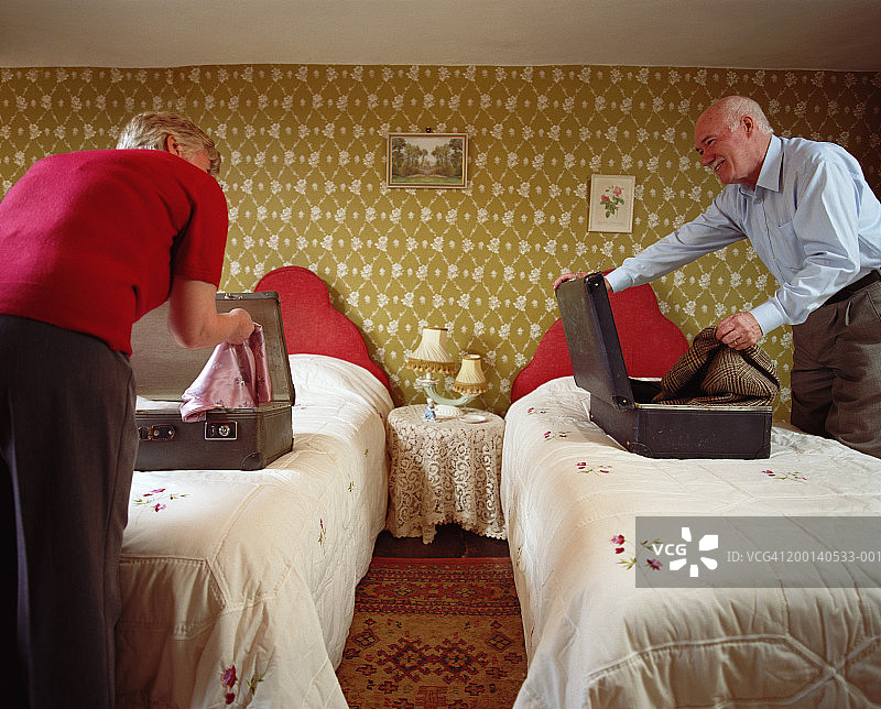 老年夫妇在单人床上打开行李箱图片素材