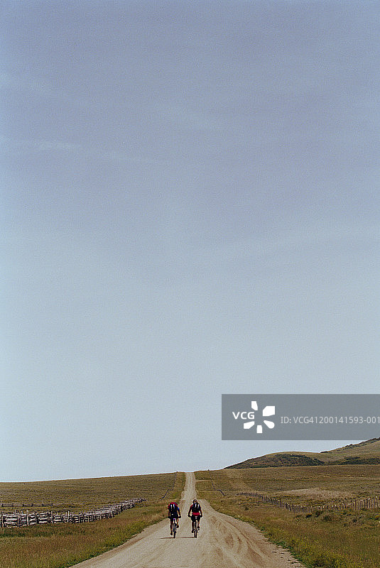 两名山地自行车手在土路上骑行，后视图图片素材