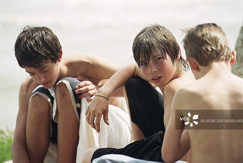 三个坐在海滩上的青少年男孩（14-16岁）图片素材