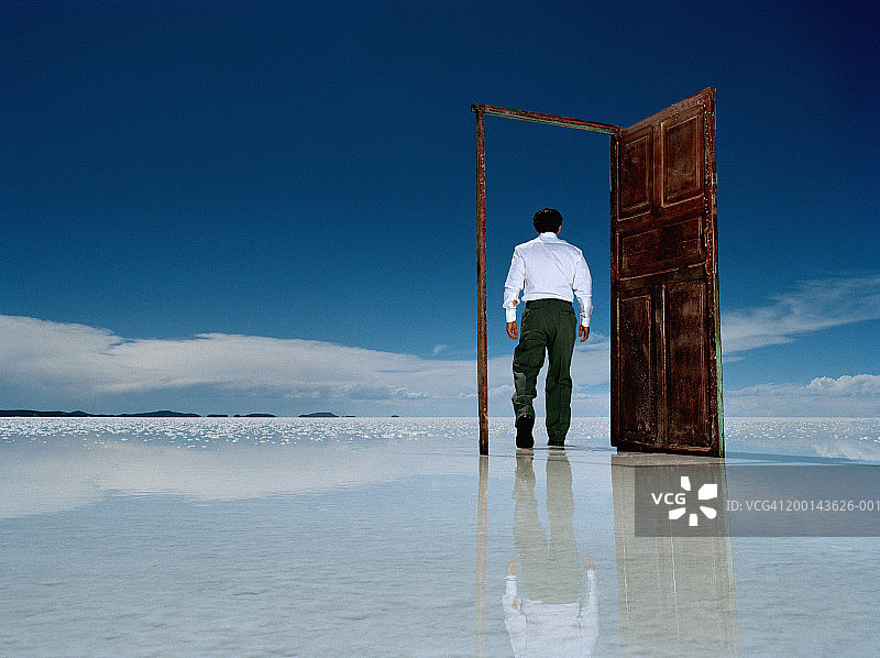 男人走过盐滩上的门，后视图图片素材