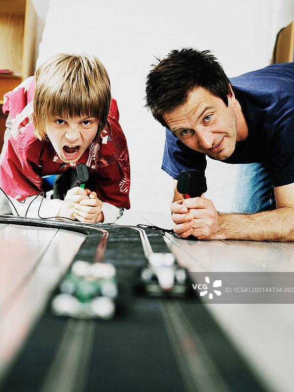 父子(9-11岁)赛玩玩具车，地面视角图片素材