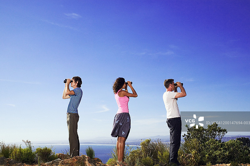 三个人在户外用双筒望远镜观察，侧视图图片素材