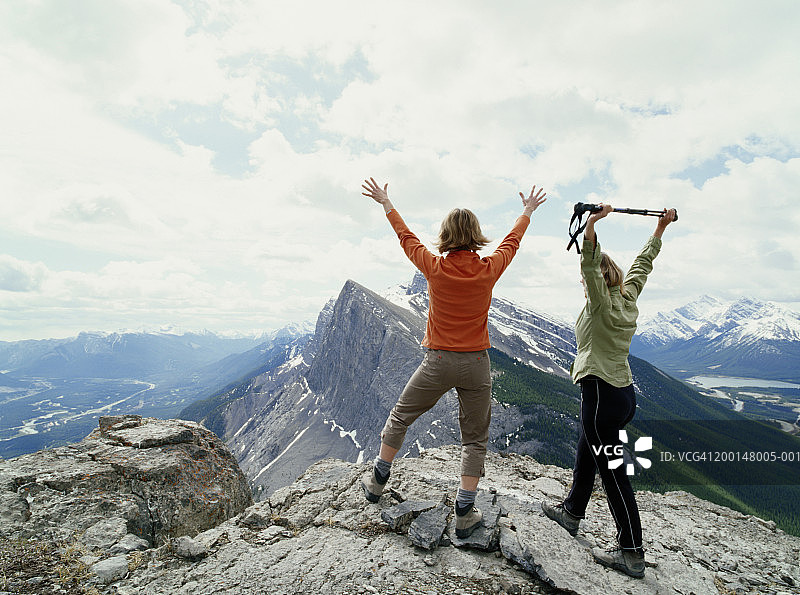 两名女人站在山顶上，举起手臂，后视图图片素材