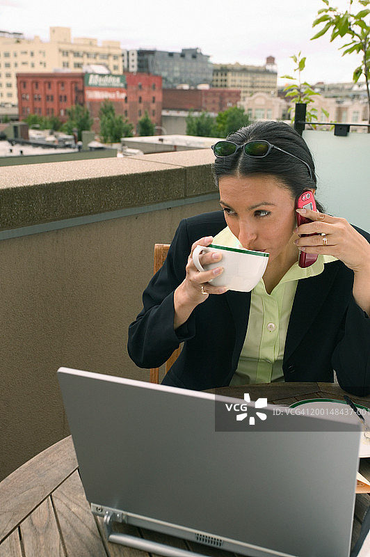 在户外餐厅使用手机喝咖啡的女商人图片素材