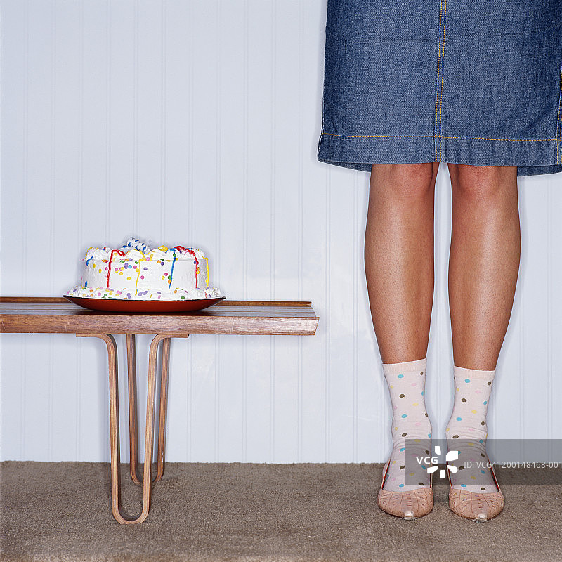 站在咖啡桌旁的蛋糕边的女人，低角度拍摄图片素材