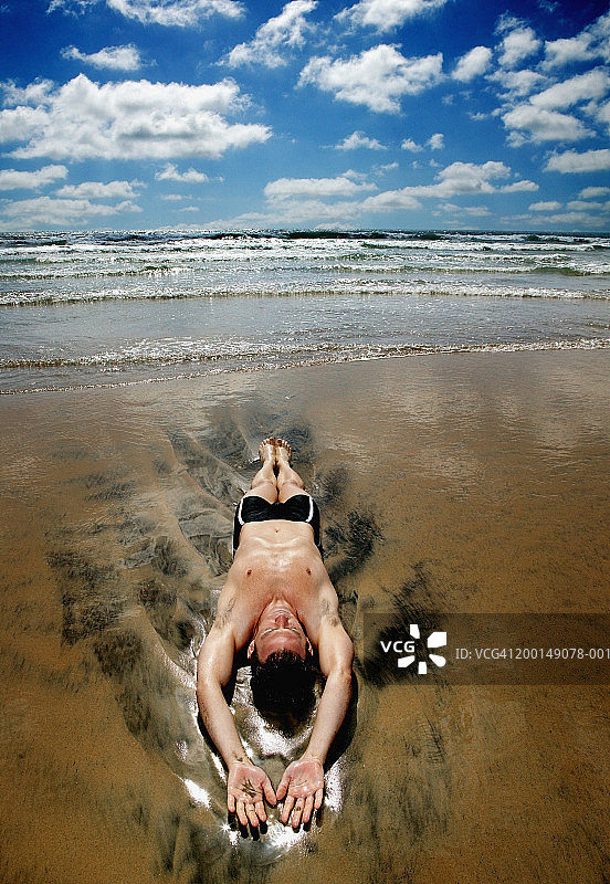 年轻男人躺在海浪中图片素材