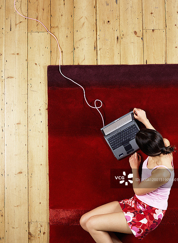 女子躺在地板上的垫子上使用笔记本电脑，俯视角度图片素材