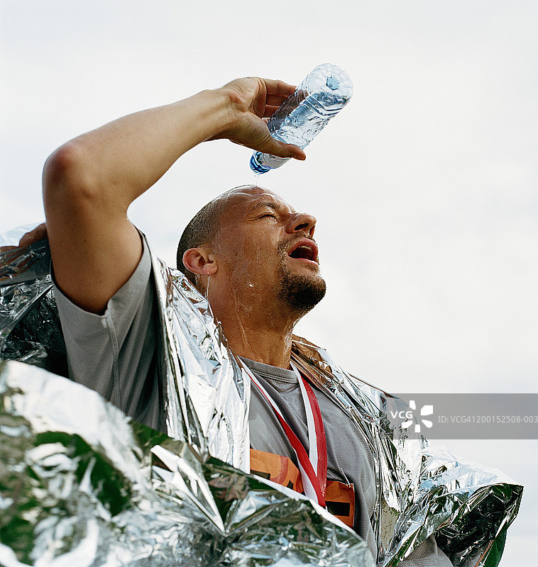 裹着锡箔毯的男人往头上倒水图片素材
