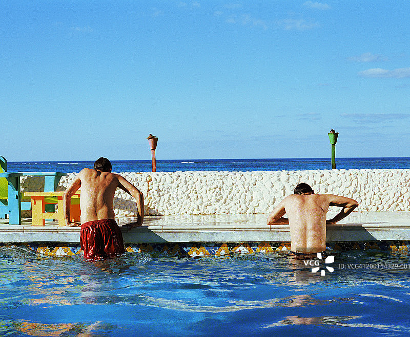 两名男子从游泳池里爬出来，后视图图片素材