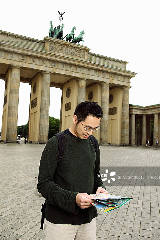 德国柏林：男子在勃兰登堡门前拿着地图图片素材