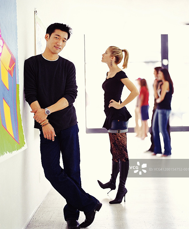 年轻人在美术馆里，男人靠在墙上图片素材
