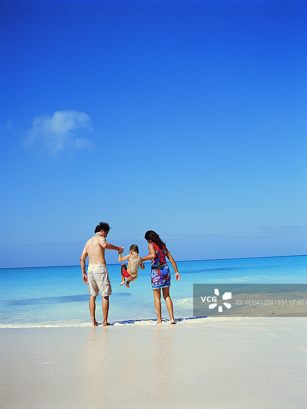 情侣在海滩上抬起男孩（6-8岁），后视图图片素材