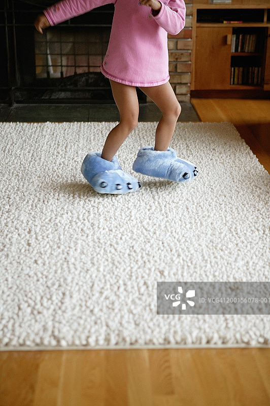 穿着毛绒拖鞋跳舞的女孩（4-6岁），低角度拍摄图片素材