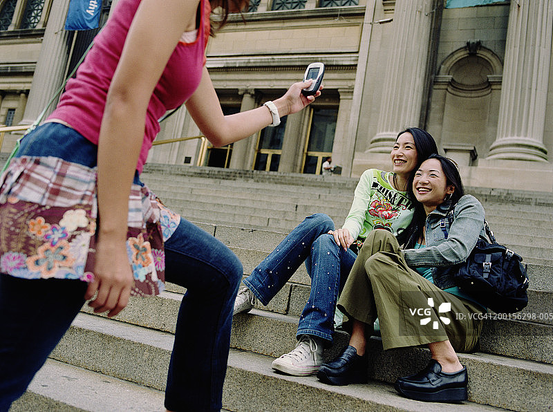 年轻女人在博物馆台阶上拍摄朋友照片图片素材