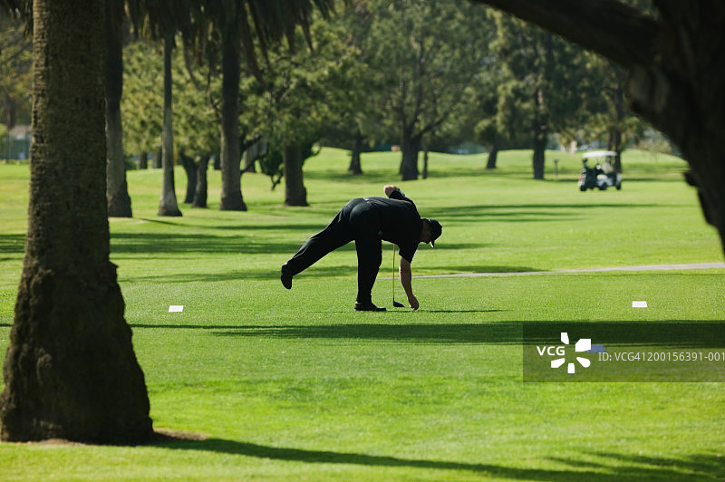高尔夫球手将球座插在草地上图片素材