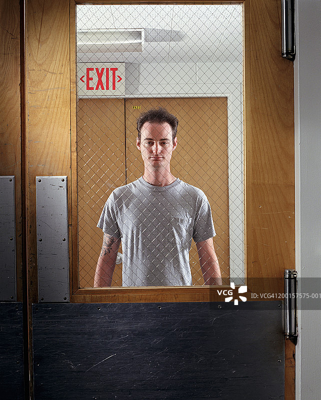 男人透过旋转门的窗户向外看，肖像照图片素材