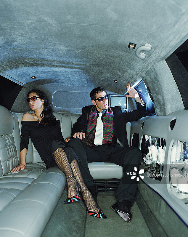 身着晚礼服和戴着太阳镜，在豪华轿车里的情侣图片素材
