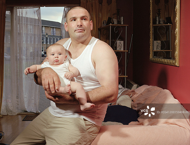 父亲抱着男婴（6-9个月大）在室内图片素材