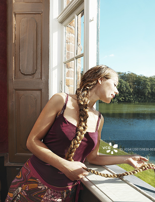 年轻女子在窗外甩着长辫子图片素材