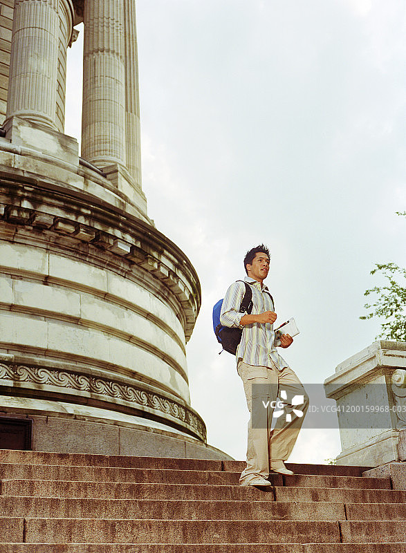 背着背包走下公园楼梯的年轻男人图片素材