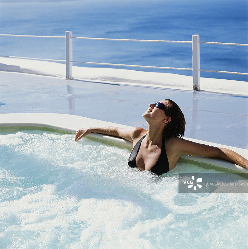 在户外水疗池中的女人，背景是海洋图片素材