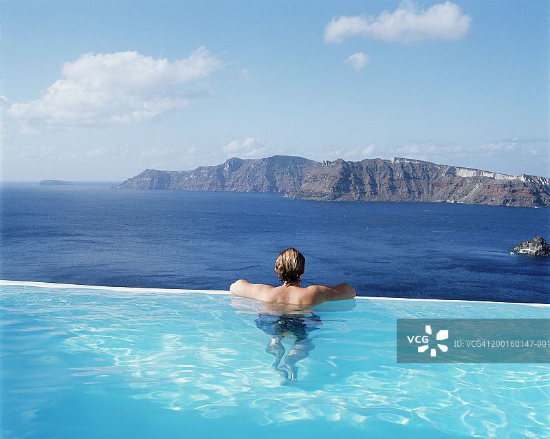 在海边的游泳池里的男人，后视图图片素材