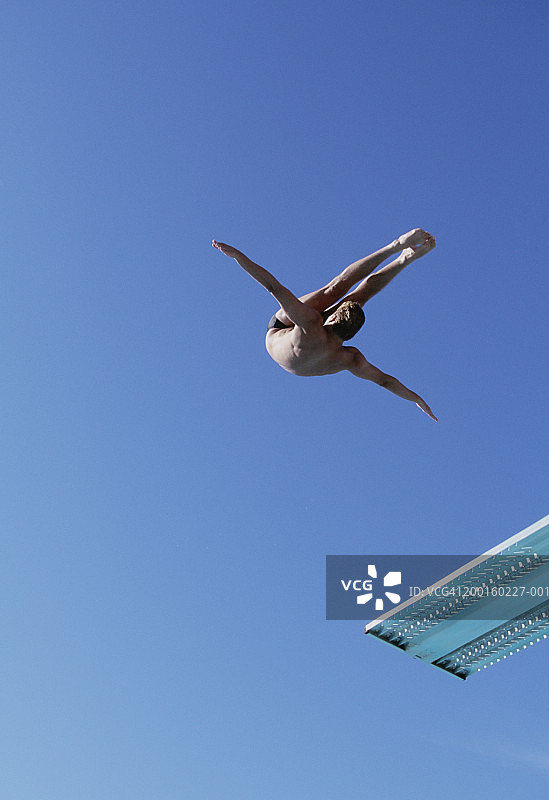 男子从跳板上跳水，低角度拍摄图片素材