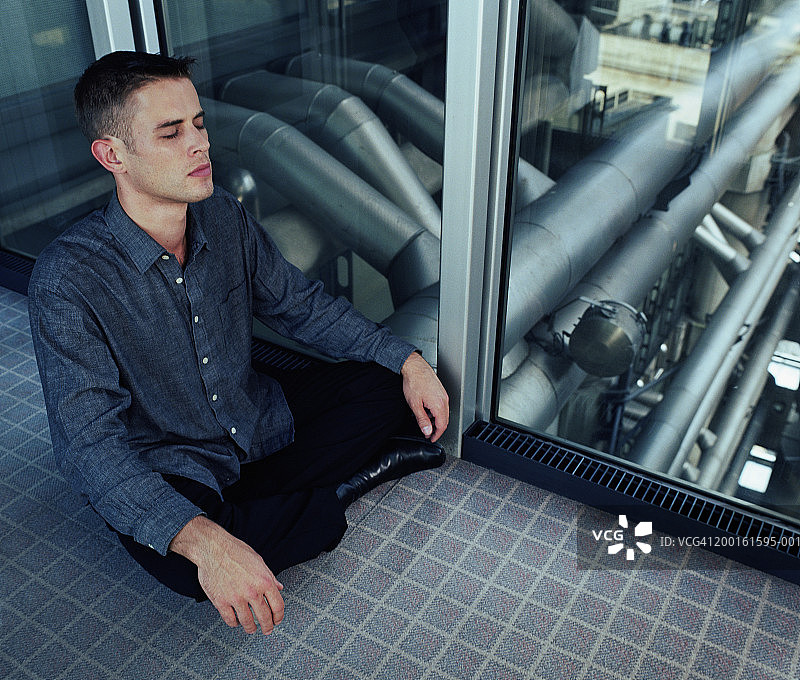 男人在办公室窗边闭着眼睛冥想图片素材
