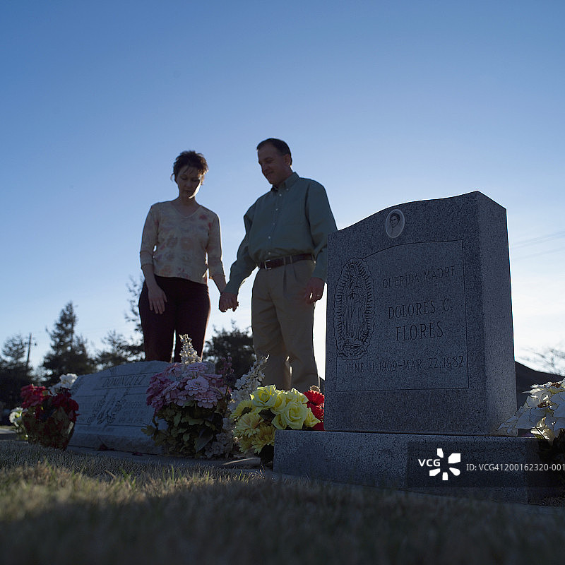 男人和女人在墓地里手牵着手（聚焦墓碑）图片素材
