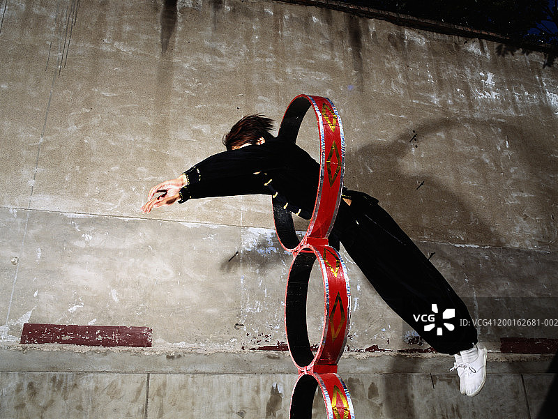 男杂技演员跳过圆环，侧面图片素材