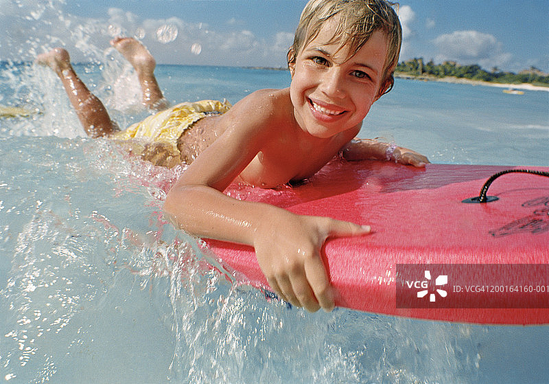 在海浪中玩趴板的微笑男孩（5-7岁）肖像图片素材