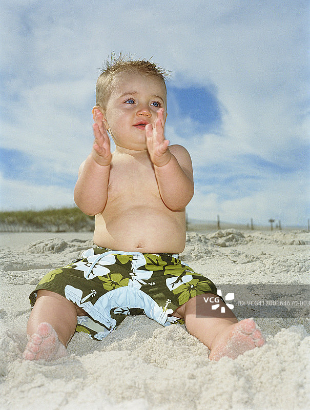 在海滩拍手的男婴（9-12个月）图片素材