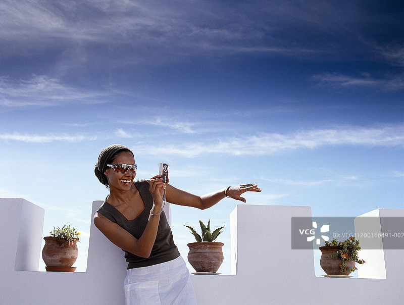 年轻女人在屋顶露台上拍照，微笑，中段图片素材