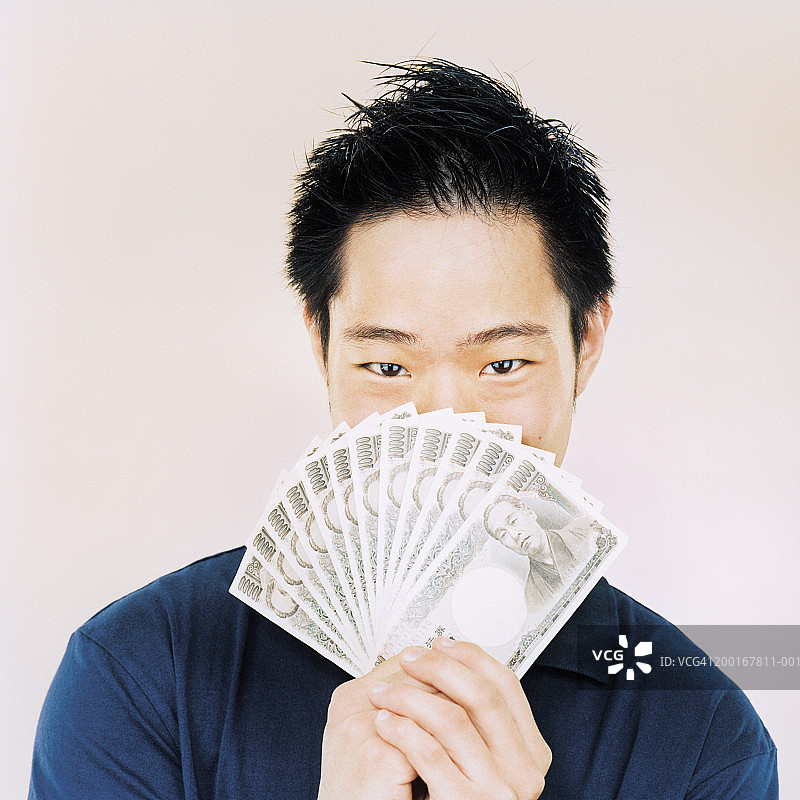 拿着银行钞票的年轻男人（遮挡部分脸部）图片素材