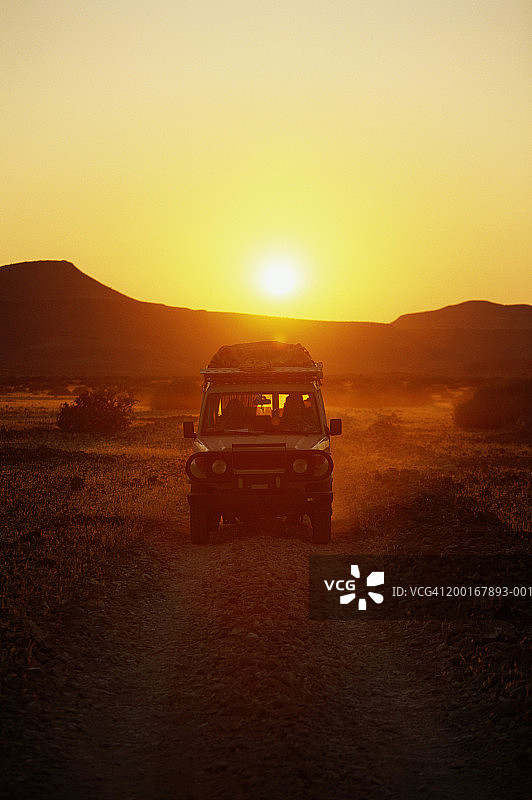 沙漠公路上日出时的4x4车辆图片素材