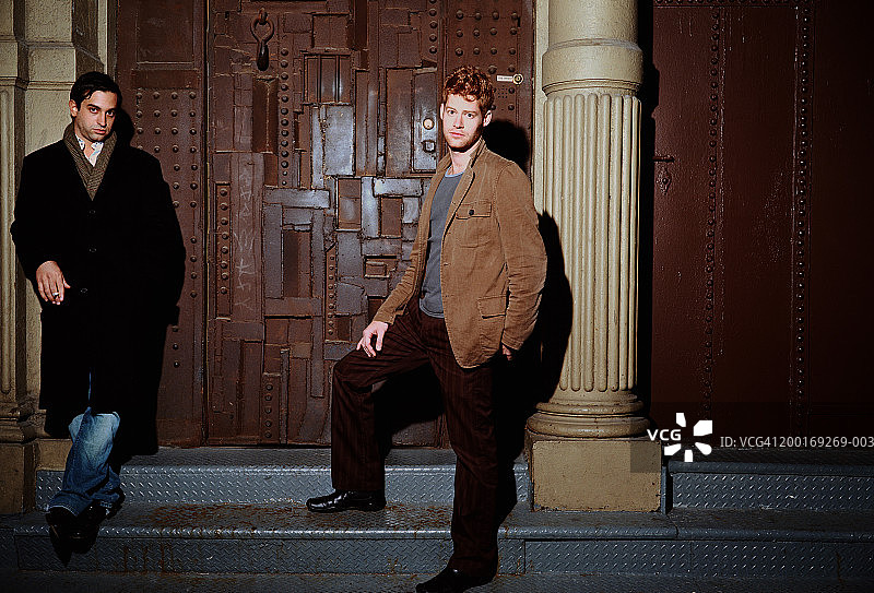 两个男人站在大门前的台阶上，一人在吸烟图片素材