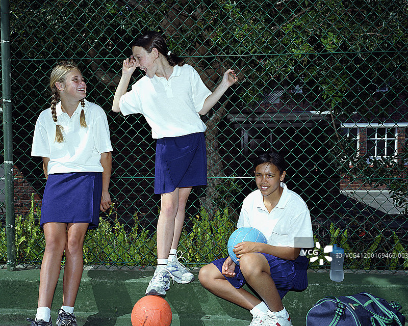 穿着无板篮球服、在球场边缘微笑的女孩们（12-14岁）图片素材