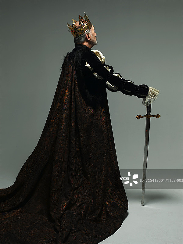 老人穿着国王的服装，带着剑，后视图图片素材