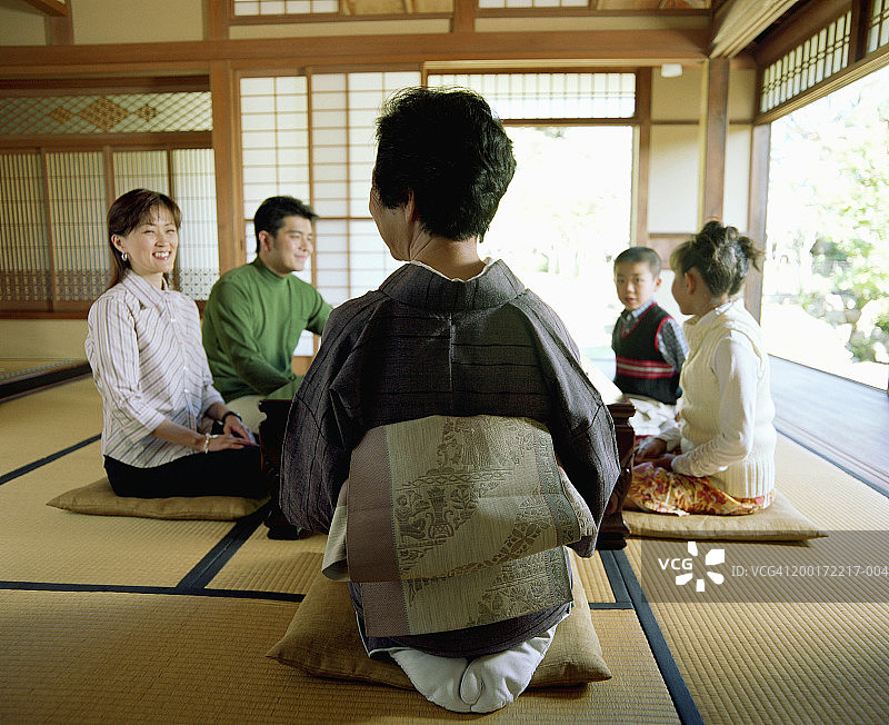 三代家庭跪在桌边的垫子上交谈图片素材