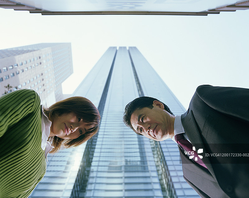男人和女人鞠躬，摩天大楼背景，仰视视角图片素材