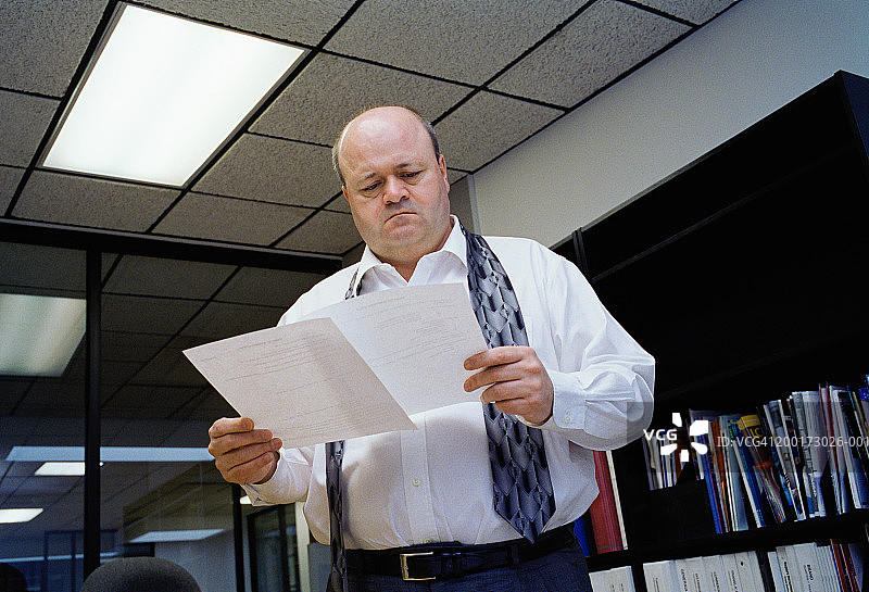 看着文书工作的商人，领带松散地挂在脖子上图片素材