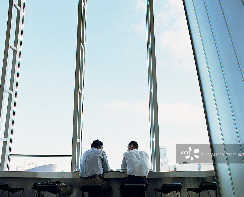 两位商人在窗边讨论（后视图）图片素材