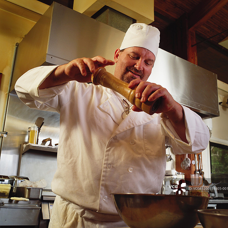 男厨师在厨房使用胡椒研磨器图片素材