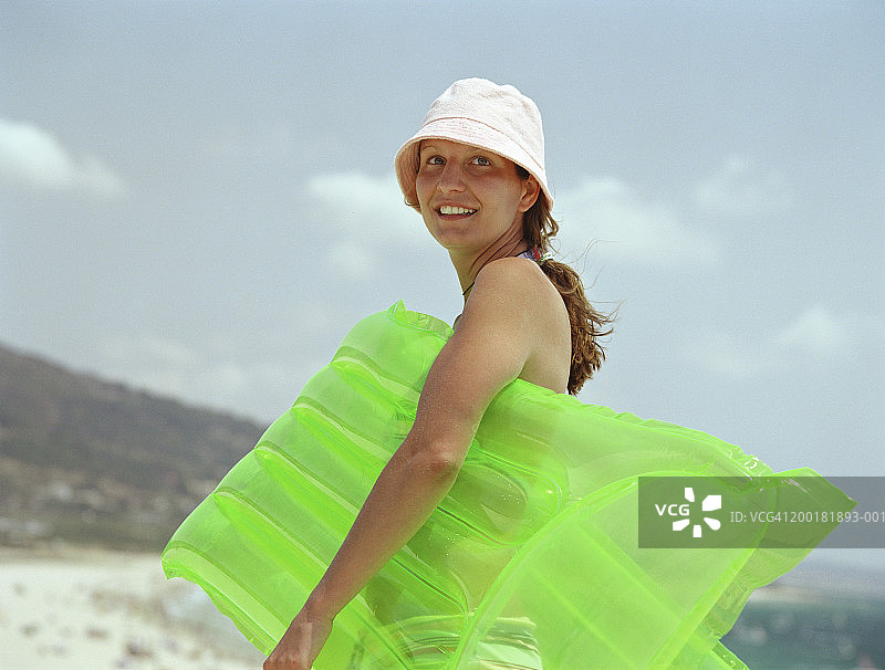 在海滩上戴着遮阳帽，携带气垫的女人图片素材