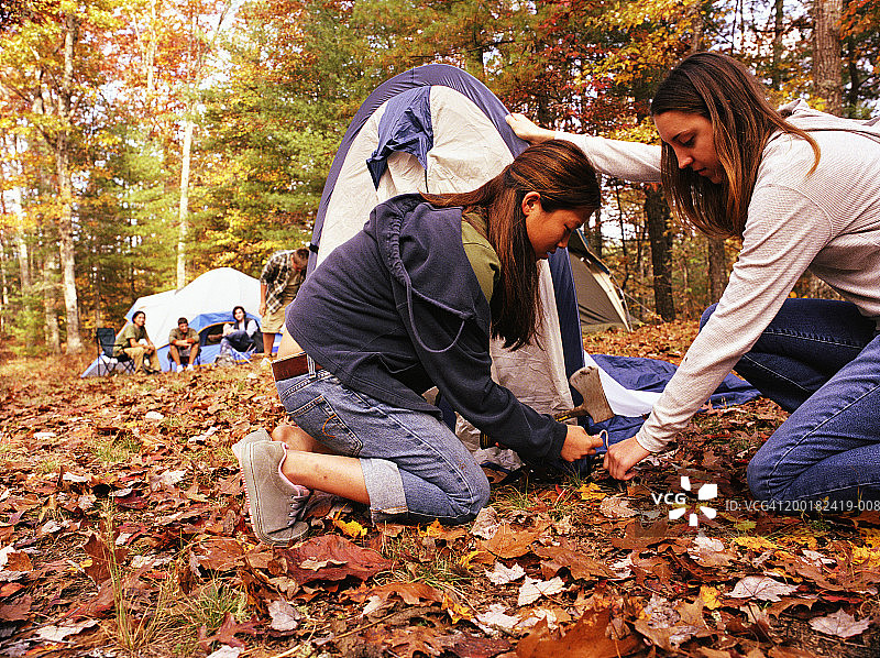 青少年女孩搭帐篷，背景有男孩图片素材